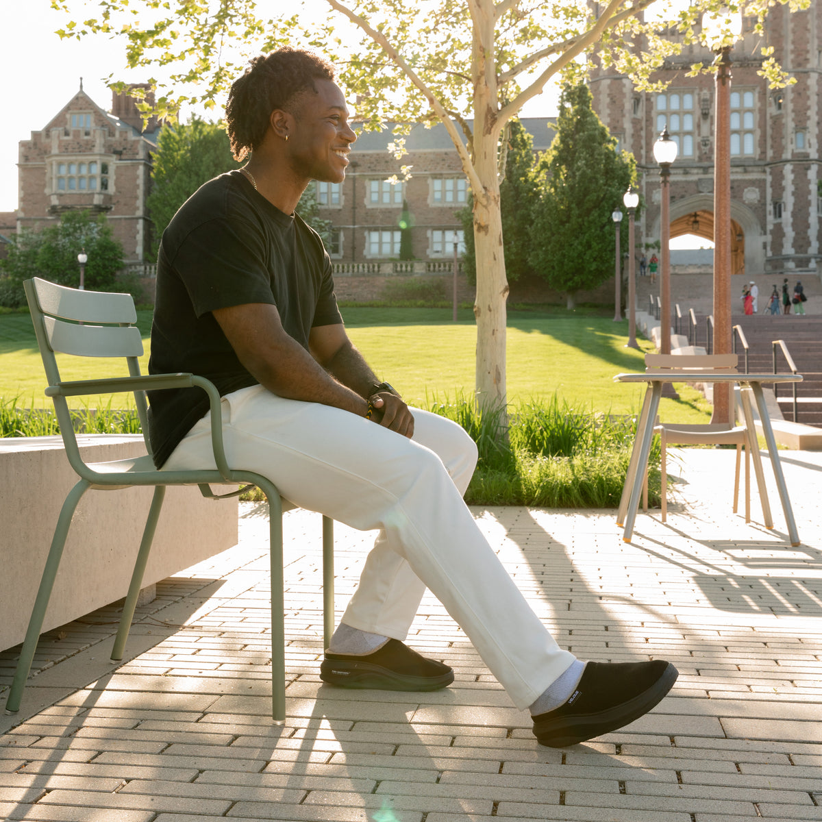VELOUS Timberline Clog in Black worn seated outdoors in late afternoon sun